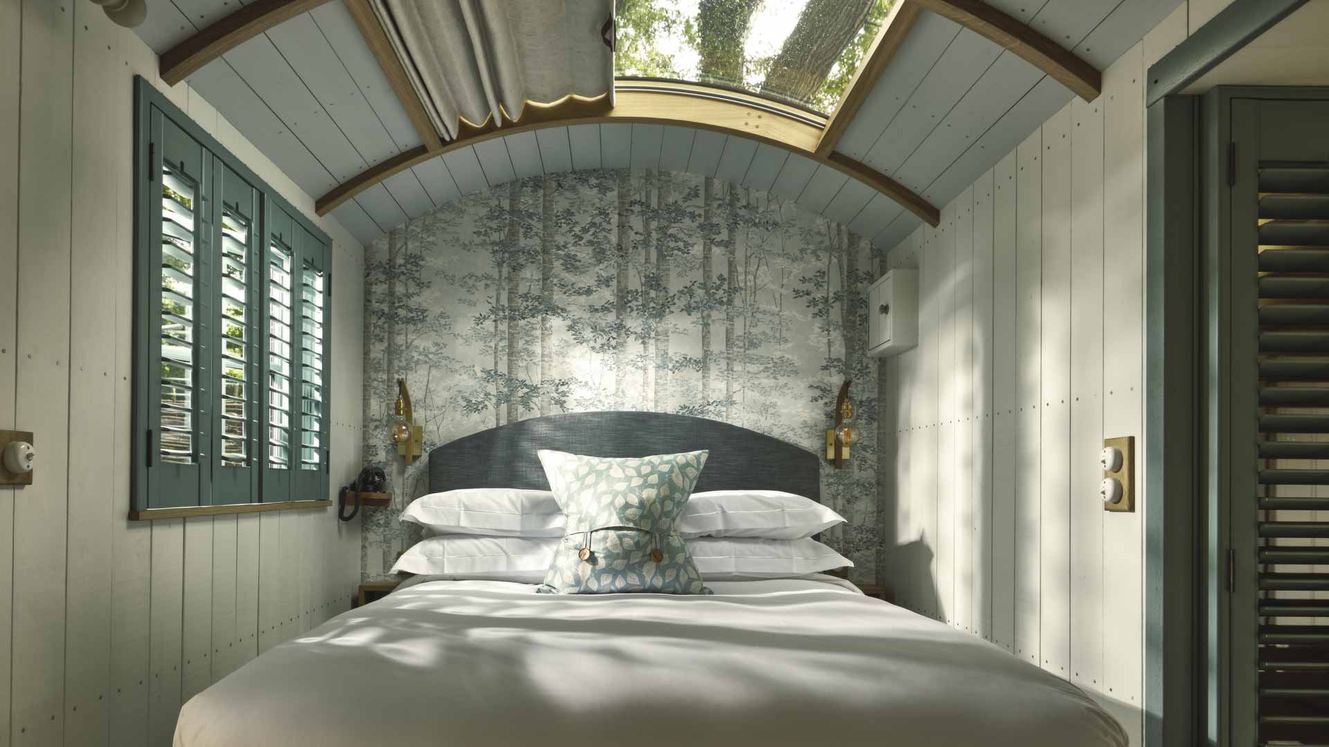 Interior of luxury shepherd hut bedroom with roll-top bath and rustic oak details