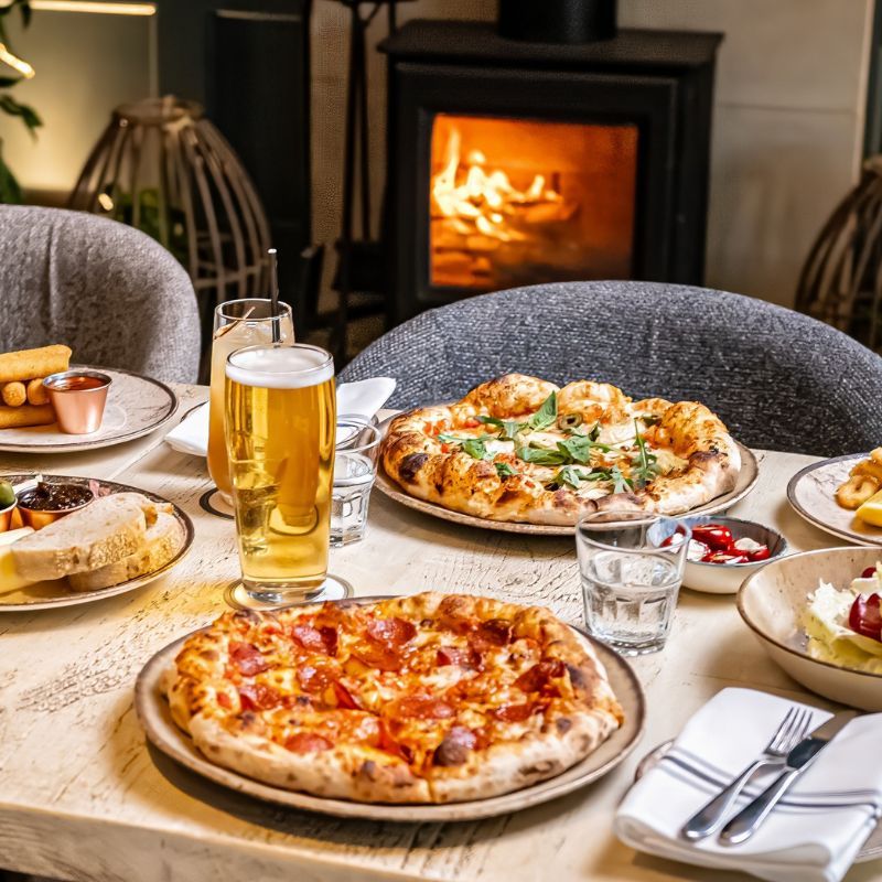 Fresh stone-baked artisan pizza served on wooden board in The Fish Hotel lounge